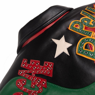 Upper back detail of black leather music jacket showing red decorative lettering, ivory star and green color-block leather panel.
