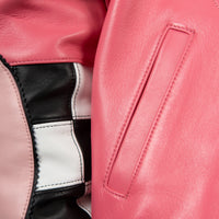 Pocket detail of coral pink leather jacket showing angled welt opening, stitched trim and contrasting black and white sleeve panels.