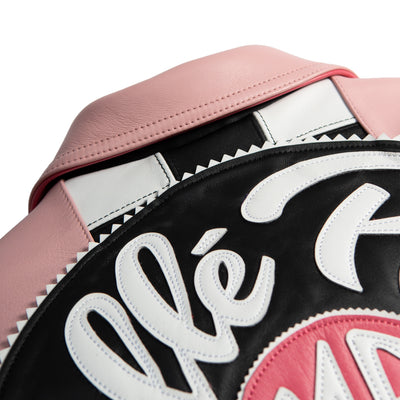 Upper back detail of pink leather jacket showing pointed collar, black and white checkerboard stripe and large round script applique.