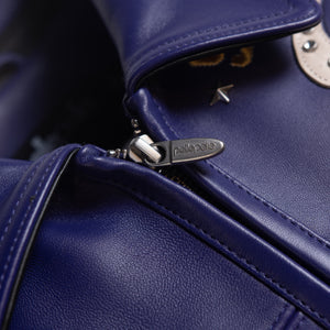 Close-up of purple leather jacket collar and central zipper showing stitched edges, metal pull and smooth genuine leather surface.