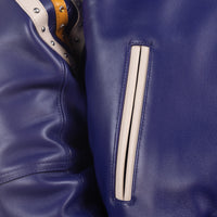 Pocket detail of women's purple leather varsity jacket showing a cream-trimmed angled welt opening and stitched leather panels.