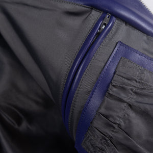 Interior detail of purple leather varsity jacket showing a vertical zip pocket, dark lining and stitched purple leather pocket trim.
